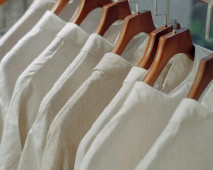 Alt text: **White apparel on wooden hangers representing SimaPro webinar topics on footwear, ESPR, DPP, and sustainability regulations